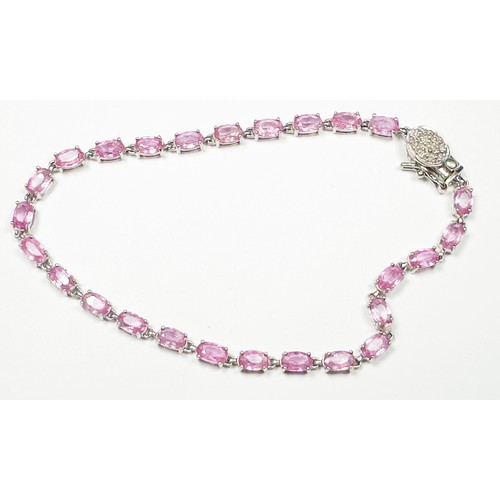 216 - A 9ct white gold bracelet, claw set with 26 x oval shaped pink sapphires, with oval pave set diamond... 