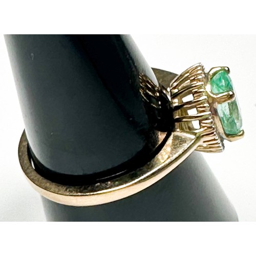 218 - A 9ct yellow gold dress ring, claw set to the centre with an oval shaped emerald, surrounded by 29 x... 