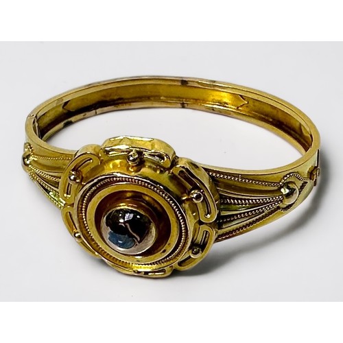 267 - A yellow metal, tests as 14ct gold or above hinged bangle, with decorative top modelled as a stylise... 