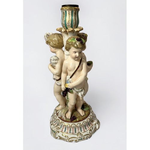 7 - A 19th century continental porcelain figural candlestick, modelled with three Putti emblematic of th... 