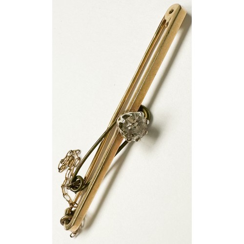 194 - A 9ct yellow gold bar-brooch with safety chain, claw set with a solitaire diamond to the centre, est... 