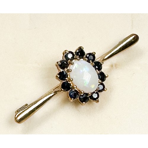 197 - A 9ct gold bar-brooch, claw set to the centre with an oval-shaped opal, surrounded by 12 x round fac... 