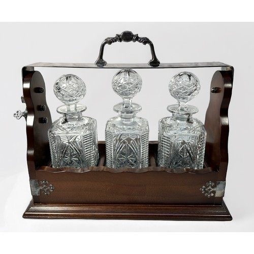 45 - A mahogany three division tantalus, with white metal mounts, lock and three glass decanters with sto... 