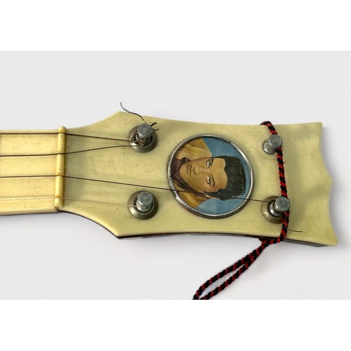 543 - A vintage Elvis Presley toy guitar by Selcol, the brown, cream and burgundy plastic four string guit... 