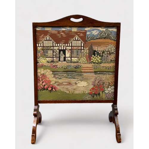 705 - A glazed tapestry fire screen, depicting a a floral garden with figure stood in the doorway of a cot... 