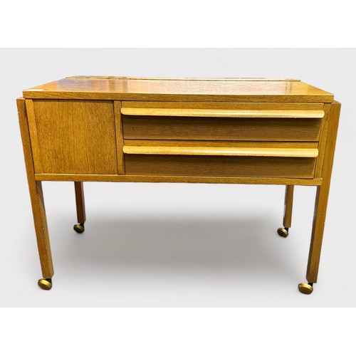 382 - A 1960s oak laminate sewing table, of rectangular form on trestle supports, with piano-hinged top en... 