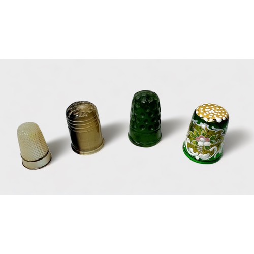 413 - A carved Spinach Jade thimble, together with a mother-of-pearl thimble, a horn thimble and Murano gr... 