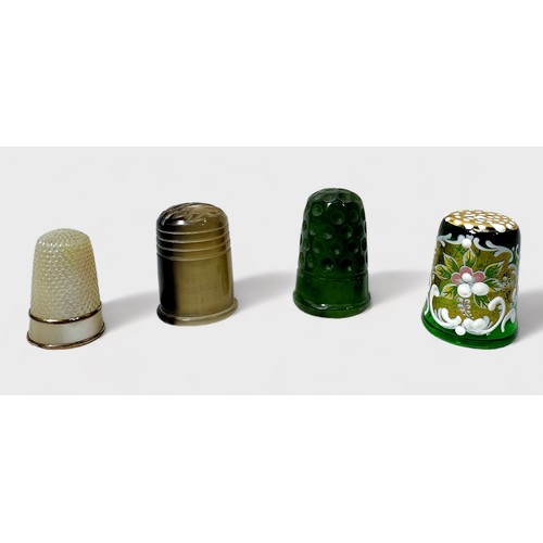 413 - A carved Spinach Jade thimble, together with a mother-of-pearl thimble, a horn thimble and Murano gr... 