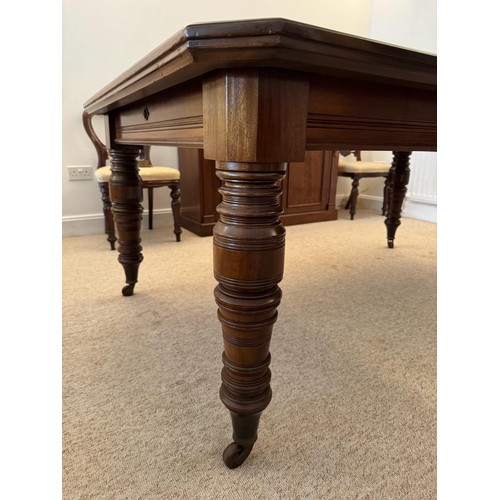 706 - A large Victorian mahogany dining table, two leaves, canted corners, raised on four turned supports ... 