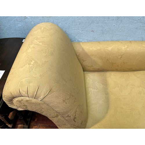 707 - A Victorian-style chaise longue, with cream foliate upholstery and matching bolster cushion, on turn... 