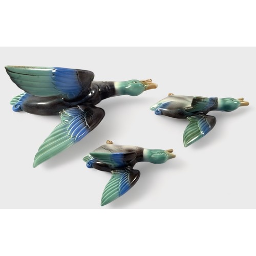 26 - A set of three Poole Pottery Art Deco wall ornaments in the form of graduating flying Mallard ducks ... 