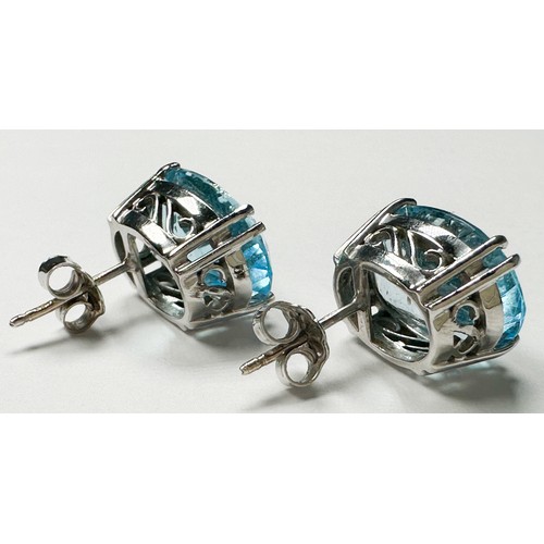 228 - A pair of 18ct white gold earrings, claw set with an oval faceted blue topaz, measuring 15mm x 11mm.