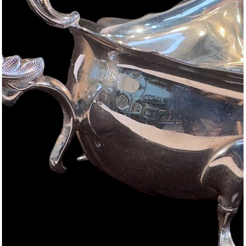 113 - An Edwardian silver sauce boat of oval bellied form with scrolled handle raised on pad feet, Birming... 