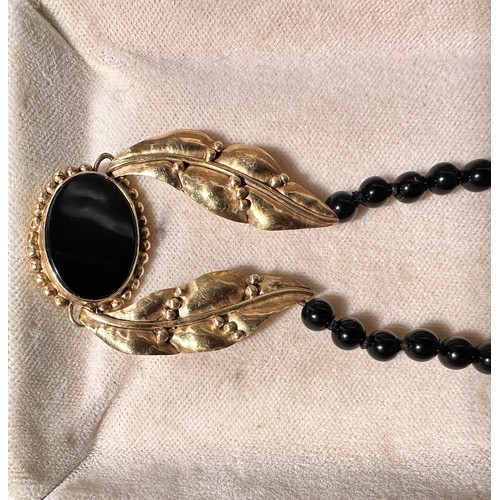 232 - A polished onyx bead necklace, set with two 18ct yellow gold shaped leaves, with an oval onyx disc t... 