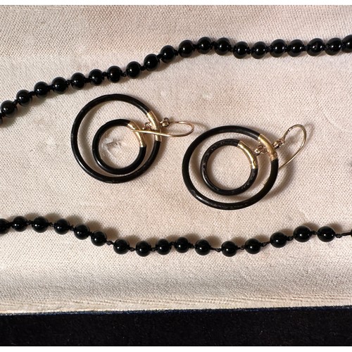 232 - A polished onyx bead necklace, set with two 18ct yellow gold shaped leaves, with an oval onyx disc t... 