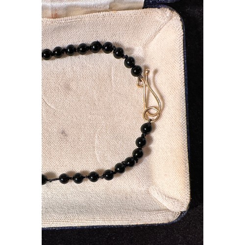 232 - A polished onyx bead necklace, set with two 18ct yellow gold shaped leaves, with an oval onyx disc t... 