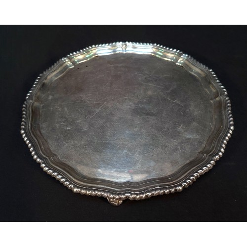 85 - A George III 'style' silver salver, of circular form with gadrooned serpentine rim, raised on three ... 