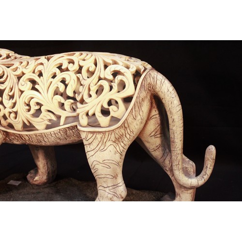 388 - A large ivory 'coloured' composite moulded and pierced model of a tiger, modelled standing on simula... 