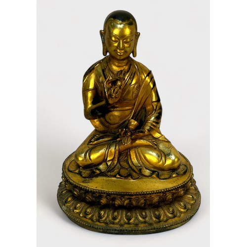 58 - A Gilt-bronze Tibetan style Buddha, seated in lotus position and holding a vajra and meditiation bel... 