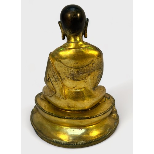 58 - A Gilt-bronze Tibetan style Buddha, seated in lotus position and holding a vajra and meditiation bel... 