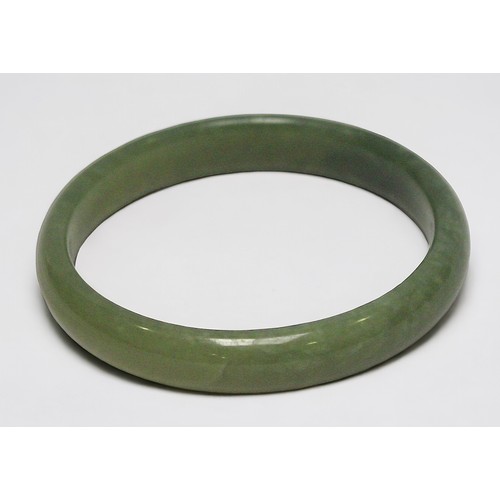 266 - A Chinese Spinach Jade bangle, with a patch of white marbling, 9.5cm diameter