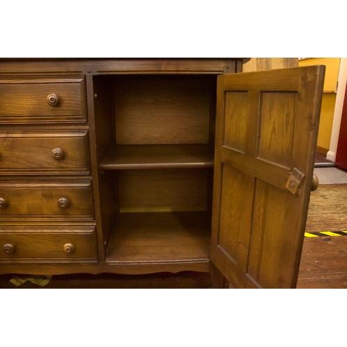 645 - An Ercol elm Colonial sideboard, comprising four short central drawers, flanked by two cupboard door... 