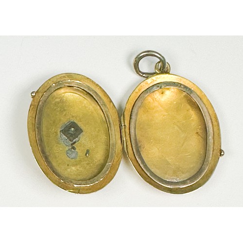 212 - A yellow metal (tests as 9ct or above) oval shaped locket, with diagonal pattern design to the back ... 