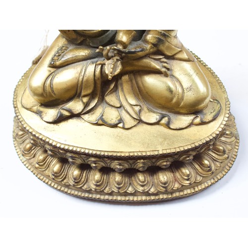 58 - A Gilt-bronze Tibetan style Buddha, seated in lotus position and holding a vajra and meditiation bel... 