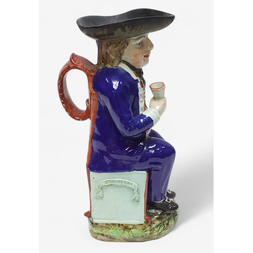 33 - A Prattware ‘Sailor’ toby jug, c1810, with blue frock coat and matching britches, a long tobacco pip... 