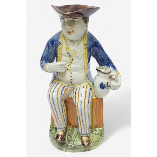 36 - A Prattware Pottery ‘Sailor’ toby jug, c1790-1810, seated holding a jug, striped britches, blue coat... 