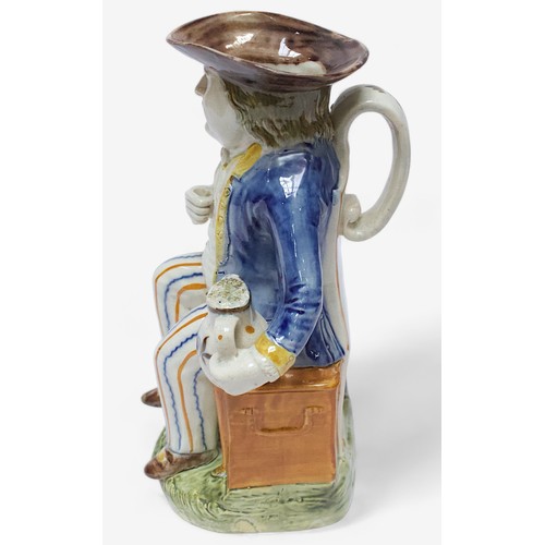 36 - A Prattware Pottery ‘Sailor’ toby jug, c1790-1810, seated holding a jug, striped britches, blue coat... 