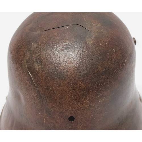 51 - A WWI German M16 Stahlhelm steel combat helmet, lacking liner and chinstrap, splits and holes to she... 