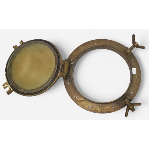 19 - An antique brass ship’s porthole, with lockable, circular, hinged window, backplate measures 38cm di... 