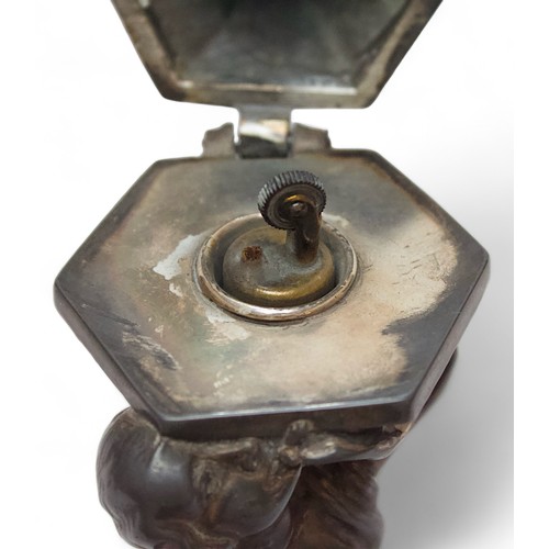 453 - An unusual silver-plated table lighter modelled as the devil’s head on a pedestal tempting a lady, t... 