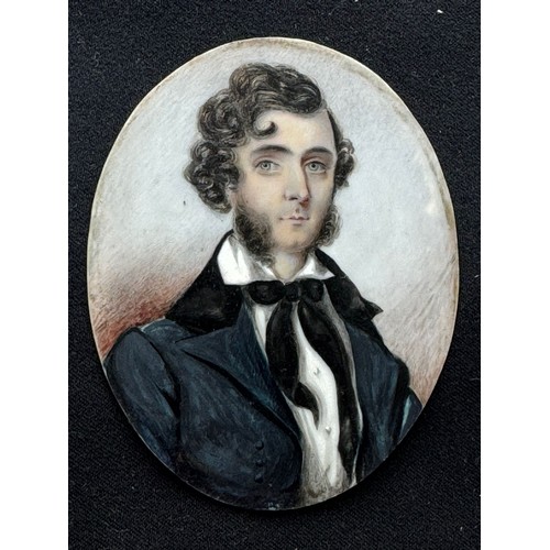 614 - A 19th century oval portrait miniature of a young naval officer, with thick black wavy hair and ‘mut... 