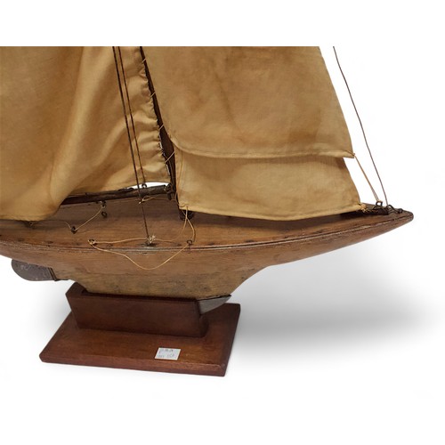 32C - An early to mid 20th Century three-sail pond yacht on stand, fully rigged over simulated plank deck ... 