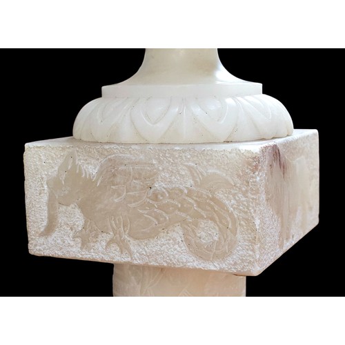 234B - (Damaged in transit) A carved alabaster urn, paired with and raised on sectional alabaster pedestal,... 