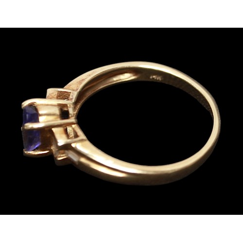 273 - A 14ct gold ring, centrally four claw set with an oval faceted tanzanite coloured stone, flanked by ... 