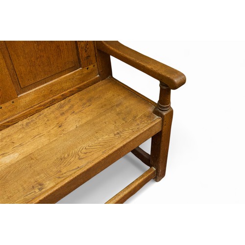 742 - An oak settle with panelled back, arm-rests to each end and raised on squared supports with stretche... 