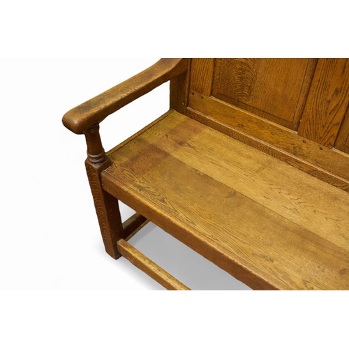 742 - An oak settle with panelled back, arm-rests to each end and raised on squared supports with stretche... 