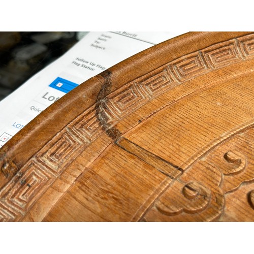 124 - A 19th century elm charger, the centre carved in relief with a dragon to a Greek Key design border, ... 