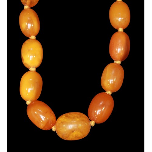 74 - A strand of graduated oval butterscotch amber beads, reportedly having been tested by the vendor, in... 