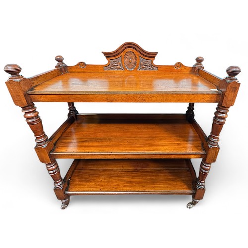 161 - An Edwardian walnut three-tier buffet, with raised carved back and on turned supports to brass sabot... 