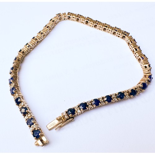 79 - A 9ct yellow gold line bracelet, set with thirty-four round sapphires, with two small round diamonds... 