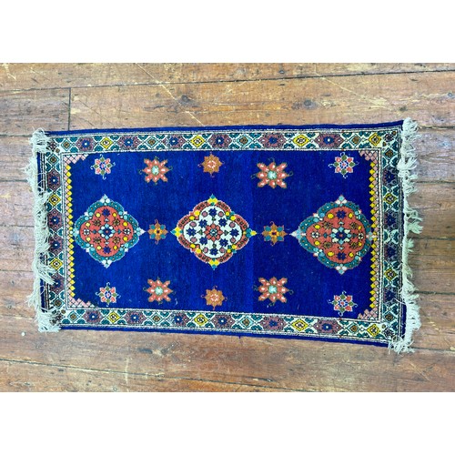 131 - A hand-knotted rug with three central guls and stylised flowers to a deep blue field, within stylise... 