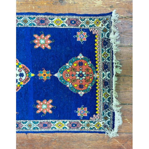 131 - A hand-knotted rug with three central guls and stylised flowers to a deep blue field, within stylise... 