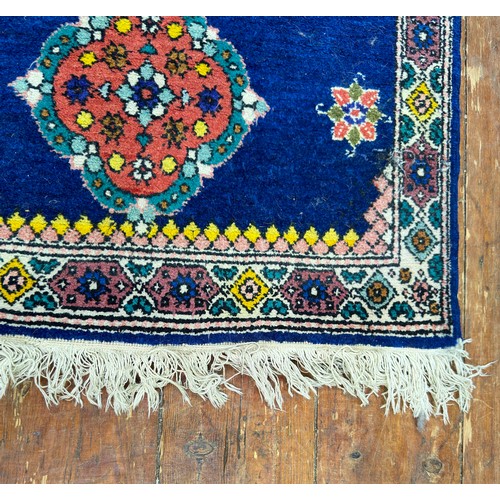 131 - A hand-knotted rug with three central guls and stylised flowers to a deep blue field, within stylise... 