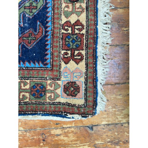 132 - A hand-knotted Caucasian runner worked with eight stylised guls to a blue field within stylised flor... 