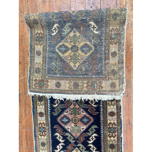 132 - A hand-knotted Caucasian runner worked with eight stylised guls to a blue field within stylised flor... 