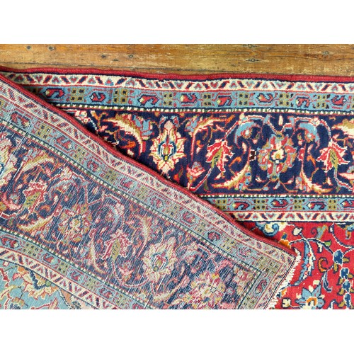 134 - A Persian medallion carpet with red central field, blue spandrels within blue Shah Abbas border, 348... 